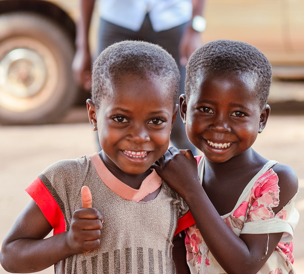 two children smiling holding together